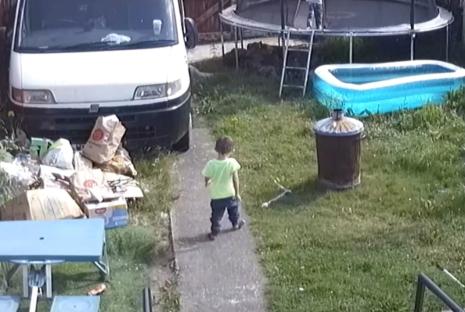 CCTV image of a toddler walking in a backyard.