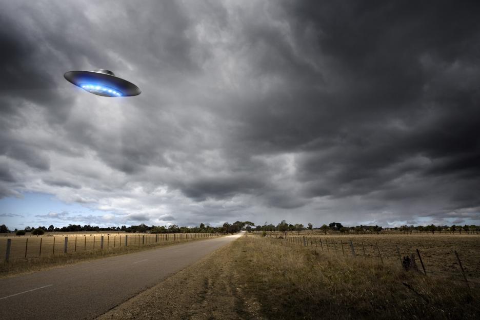 Illustration of a UFO over a country road.