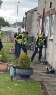 Police officers struggling to break down a door.