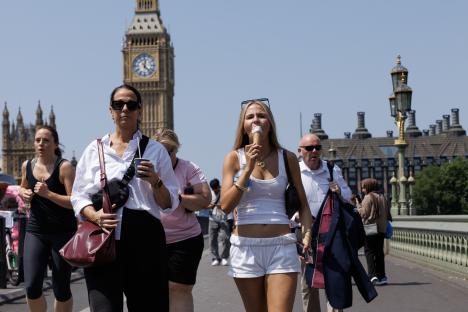 People walking across Westminster Bridge in London on a hot day, some eating ice cream.