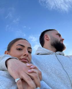 Couple holding hands against a blue sky.
