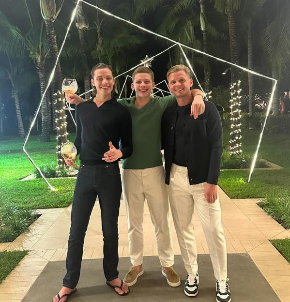 Three men posing together, holding wine glasses.