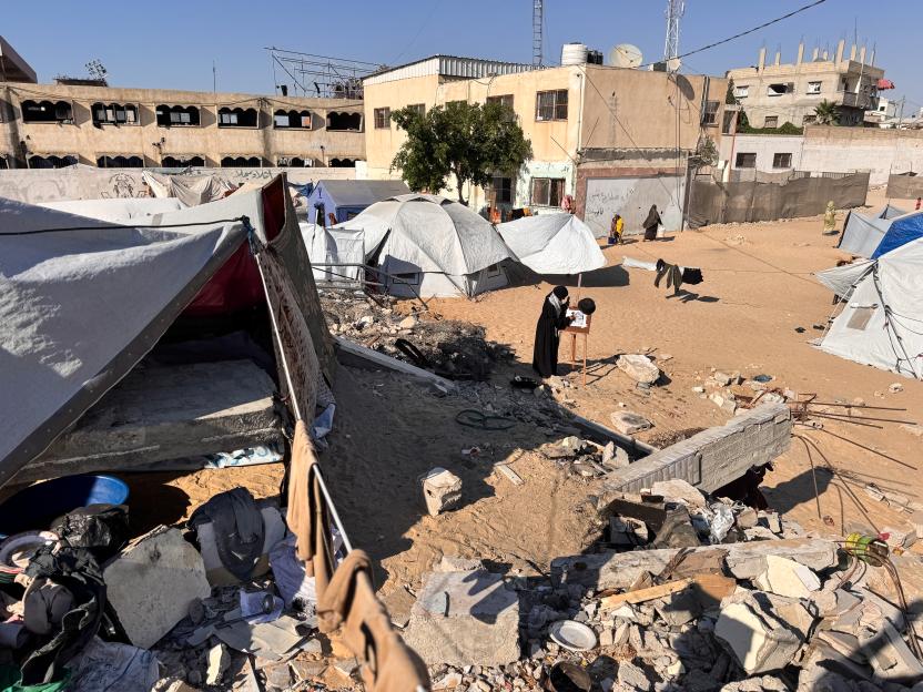 Palestinian painter Ragde Sheikh al-Eid painting amidst rubble and tents in Khan Yunis, Gaza.