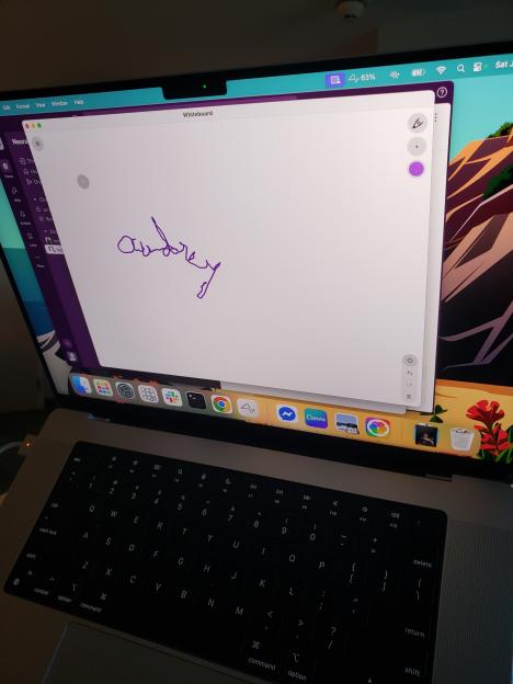 Laptop screen showing a purple signature on a whiteboard app.