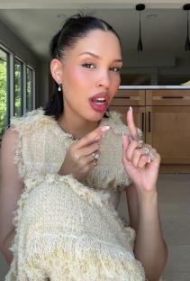 Woman in a beige dress explaining something.