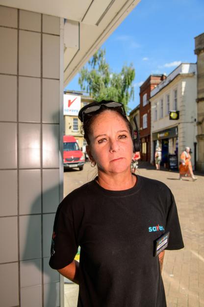 A woman wearing a Savers uniform stands outside in Trowbridge.