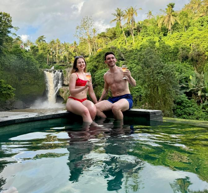 Couple enjoying drinks by a waterfall in Bali.