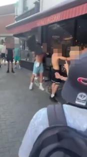 A group of people fighting outside a restaurant.