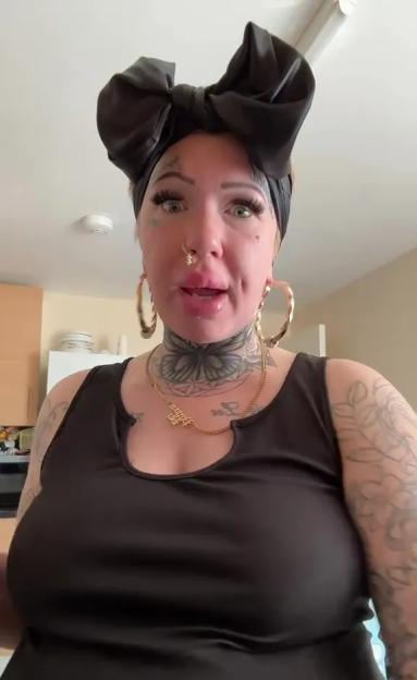 Woman with tattoos and a large black bow in her hair speaks to the camera.