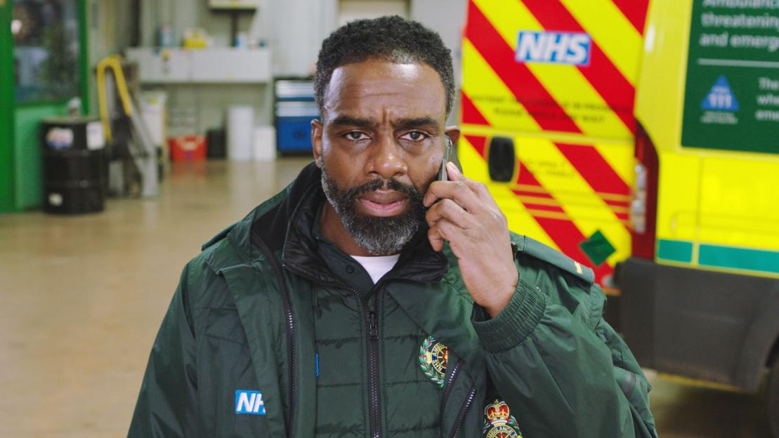 Paramedic on phone outside ambulance.