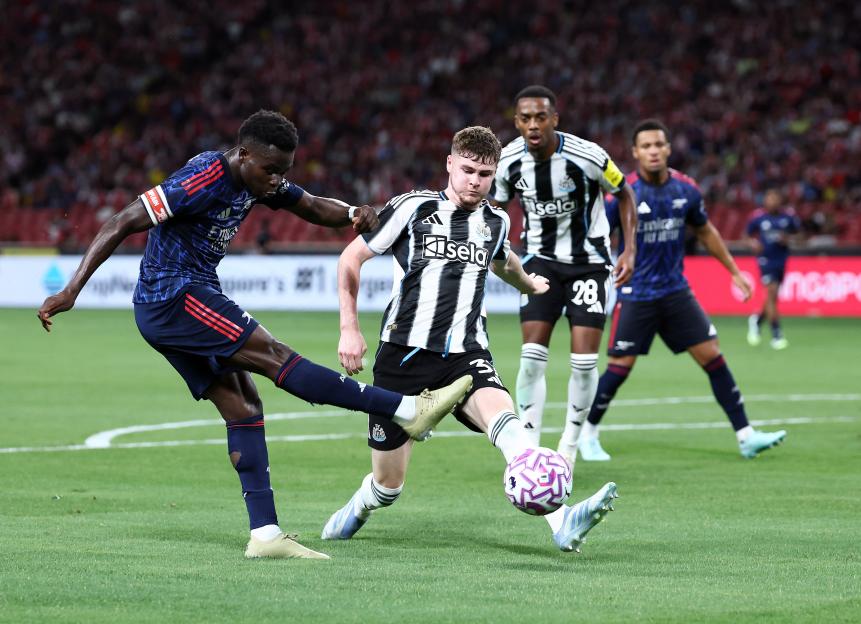 Bukayo Saka of Arsenal shoots past Alex Murphy of Newcastle United during a soccer match.