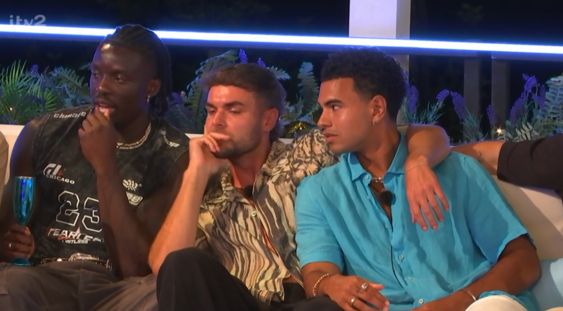 Three men sitting together, one with his arm around another.