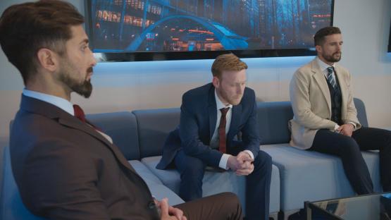 Three men in suits sitting on a couch.