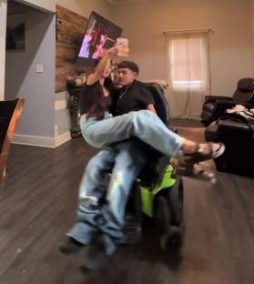 Woman playfully lifts her disabled partner in his wheelchair.