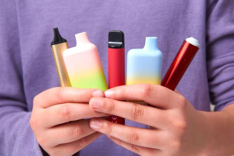 Boy holding several vaping devices.