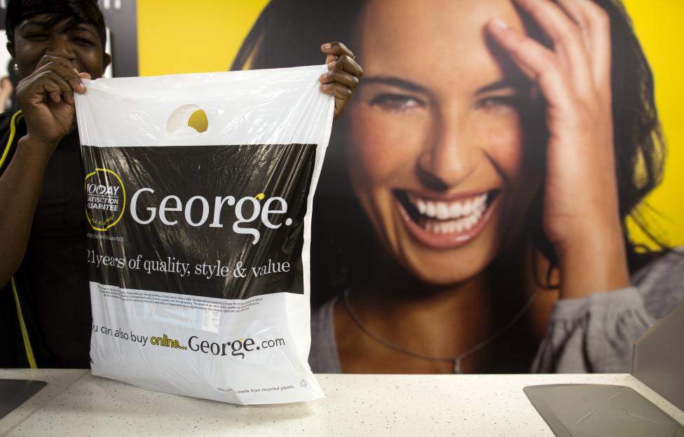 A cashier holds up a George clothing bag in an Asda supermarket.