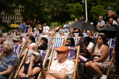 People relaxing in deck chairs in a park on a hot day.