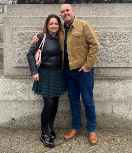 Couple posing in front of a lion statue.