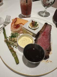 A plate of food including prime rib, shrimp, asparagus, and deviled eggs.
