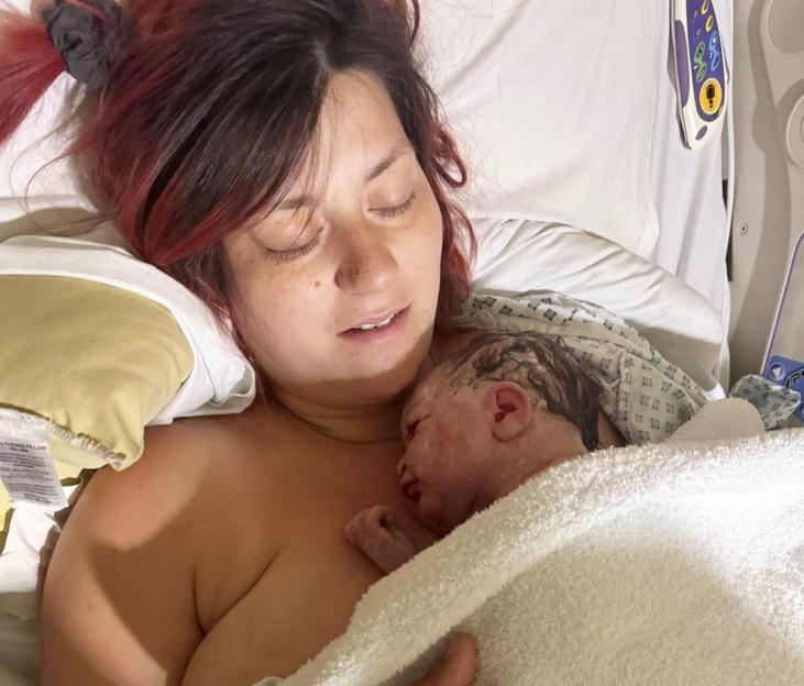 A mother holding her newborn baby in a hospital bed.