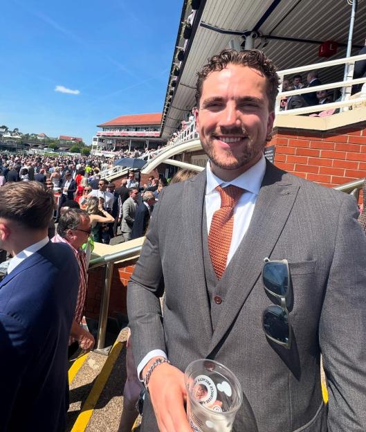 Man in suit at a racecourse.