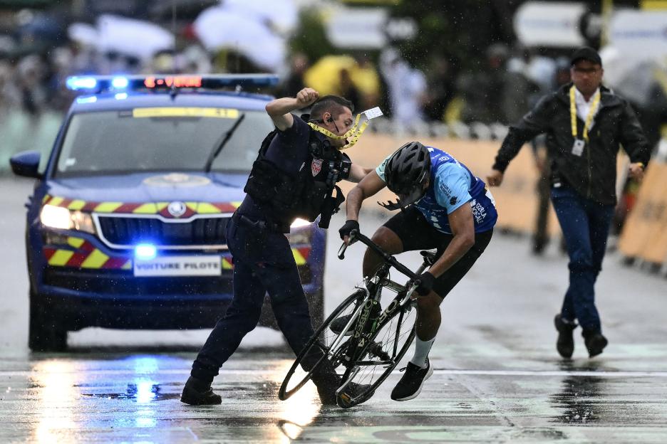 A French CRS officer stops a cyclist attempting to cross the Tour de France finish line.