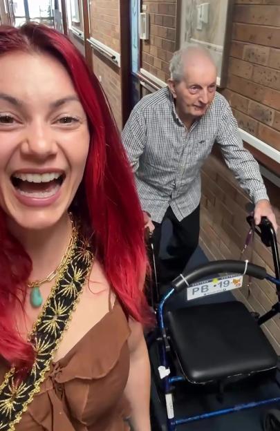 A woman and her grandfather walking down a hallway.