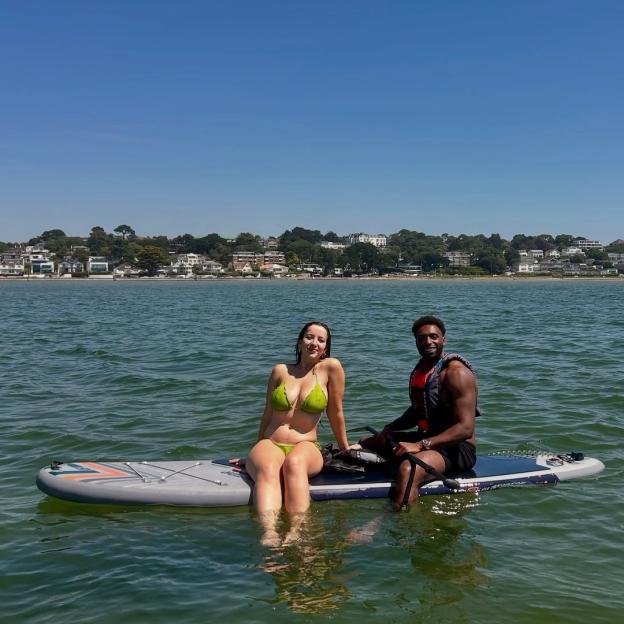 Couple paddleboarding on calm water.
