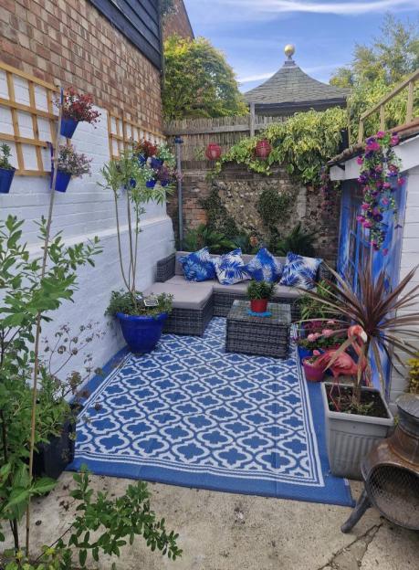 Santorini-themed garden patio with blue and white patterned rug, seating area, and plants.