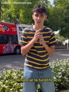 A young man speaking in front of a tour bus.