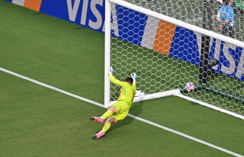 Benfica's goalkeeper Anatoliy Trubin diving to unsuccessfully stop a goal.