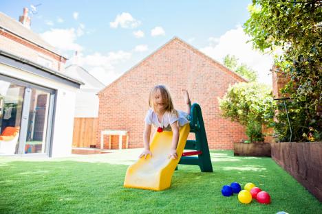 Girl playing on a slide in a backyard.