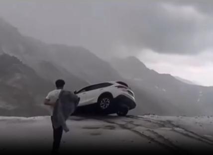 People rescuing a car dangling over a cliff.