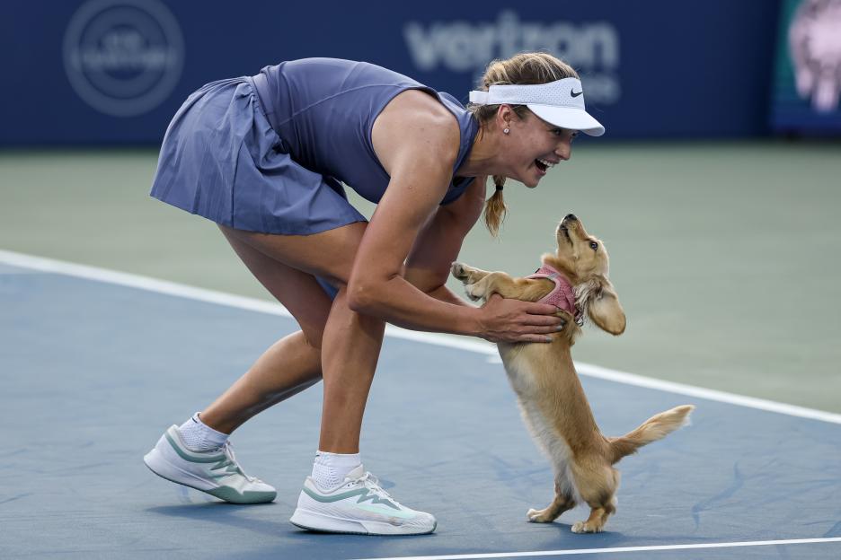 Anna Kalinskaya celebrates with her dog, Bella, on a tennis court after winning a match.