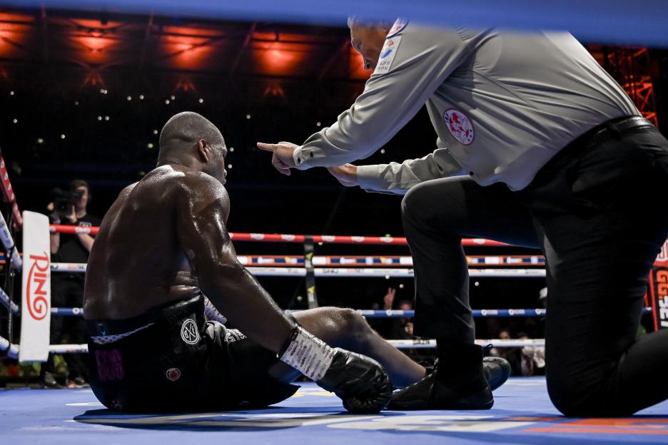 Boxer Daniel Dubois sits on the canvas after being knocked down by Oleksandr Usyk.