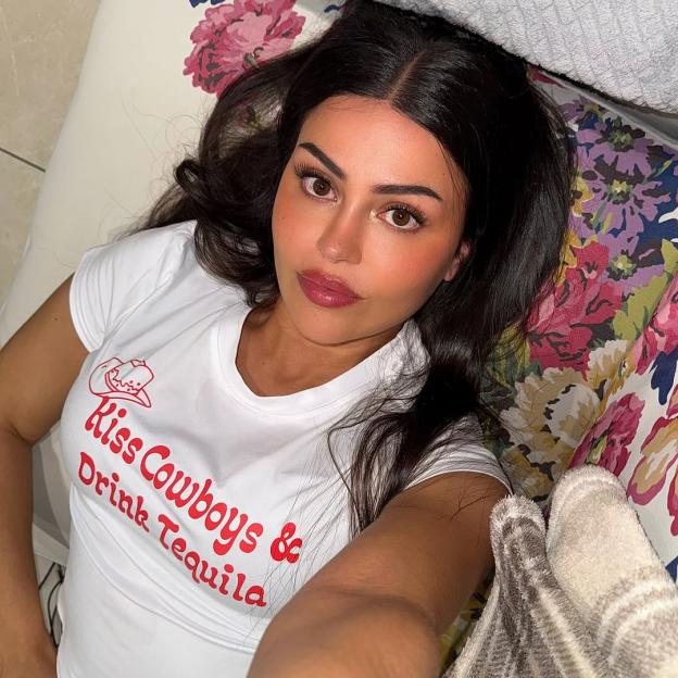 Woman lying down wearing a white shirt that says