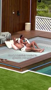 Love Island couple relaxing on a hammock by a pool.
