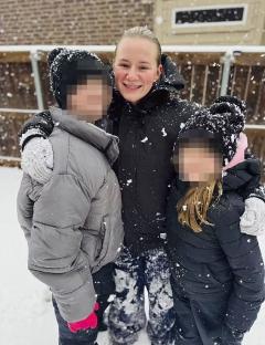 Woman playing in the snow with two children.