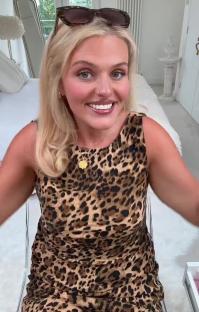 Woman in leopard print dress smiling at camera.