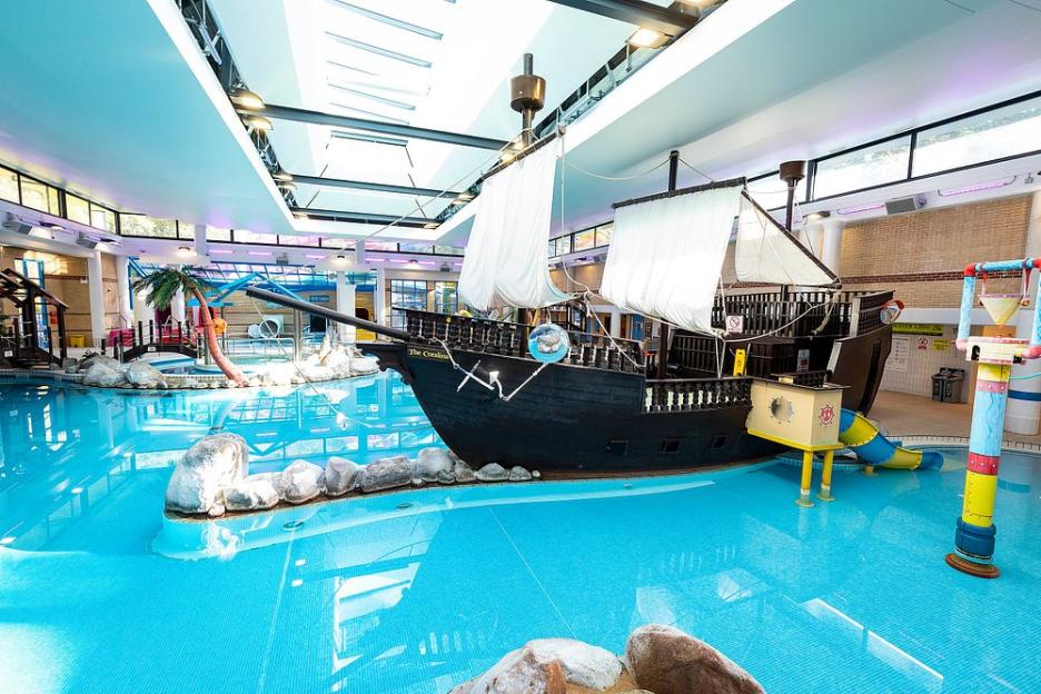 Indoor pool with pirate ship play structure.