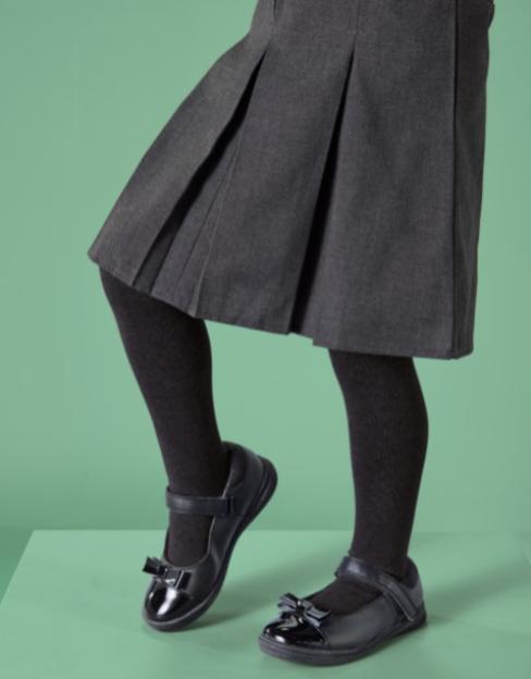Girl wearing black school shoes and grey pleated skirt.