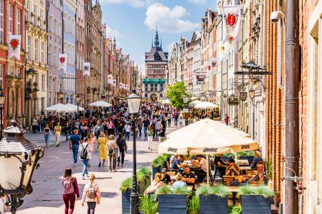 Tourists strolling through Gdansk's Old Town, with cafes and the Golden Gate in the background.