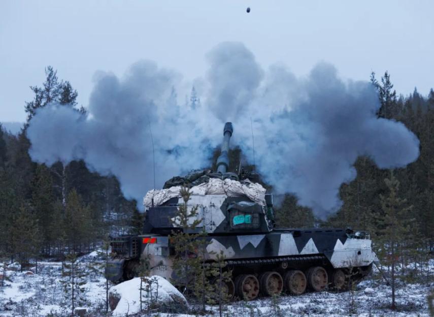 Self-propelled howitzer firing in snowy forest.