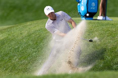 Jordan Spieth hitting a golf ball from a sand trap.