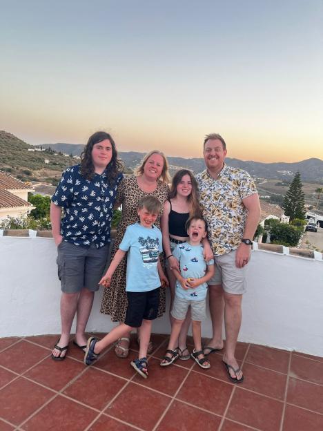 Family portrait of five people on a patio overlooking a hillside.