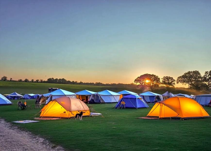 Sunset over a campground with numerous tents.