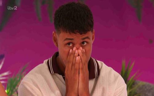 Man covering his mouth with hands at the fire pit on Love Island.