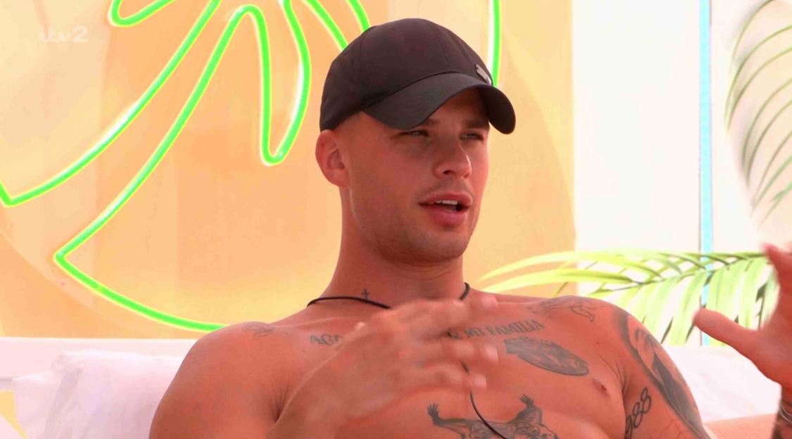 Man in baseball cap speaks on Love Island.