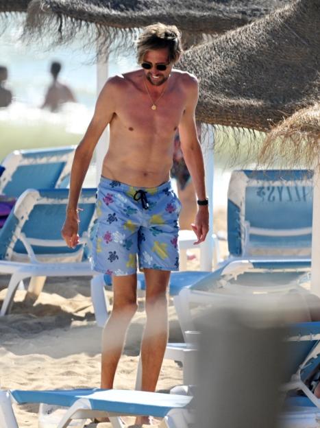 Peter Crouch on a beach wearing turtle-patterned swim shorts.