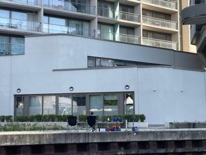 Two chairs sit outside a building near a canal.